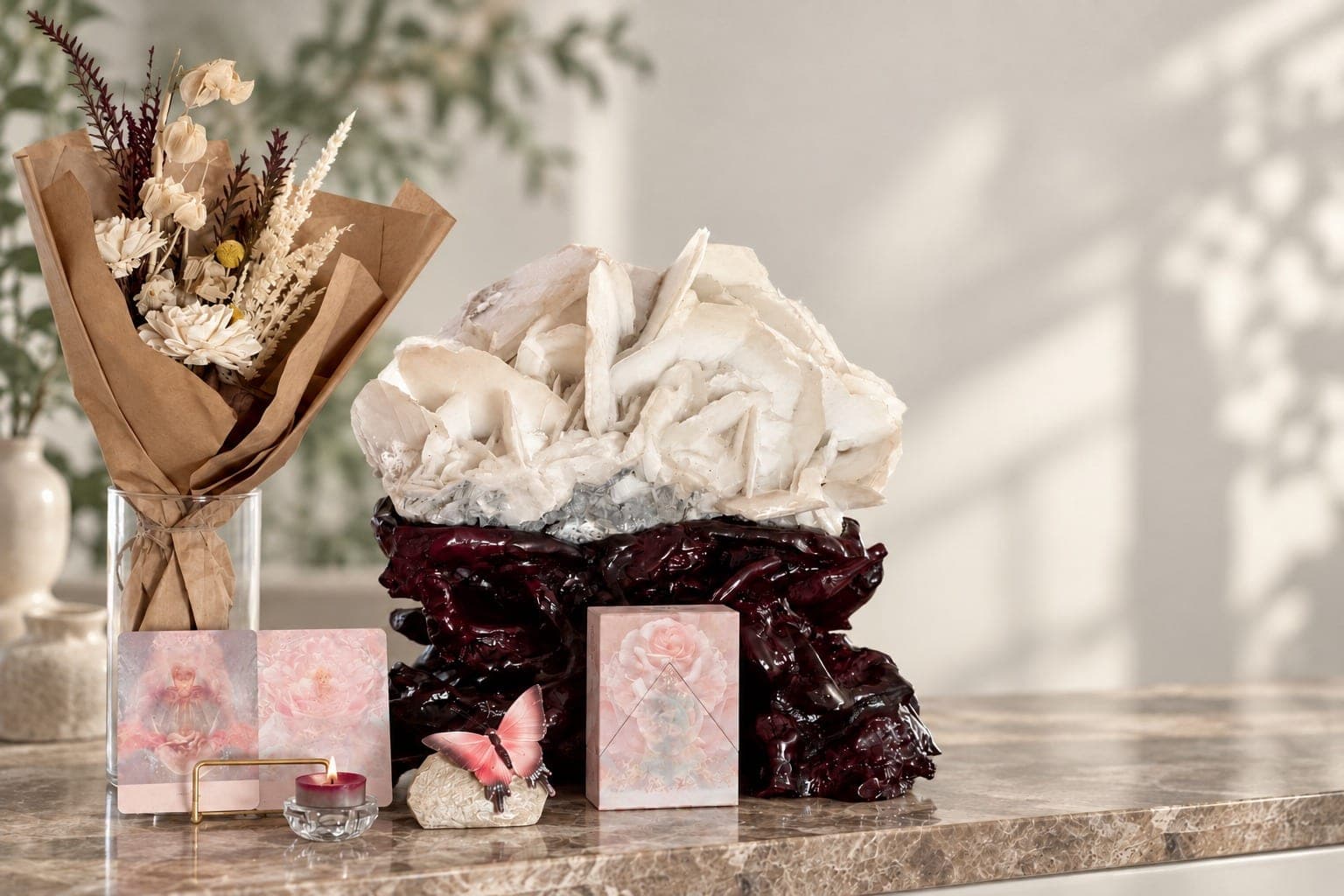 A selenite cluster with dried flowers and a candle